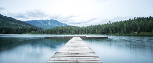 View of a lake from a long pier looking towards mountains in the distance