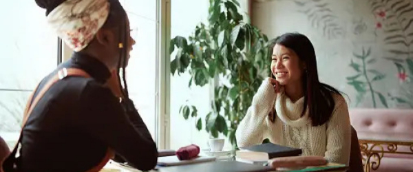 Black woman and Asian woman conversing with smiles